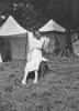 1912 girl on tree stump in front of tents (1912)