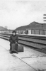 Girl with suitcase on railroad platform (1913)